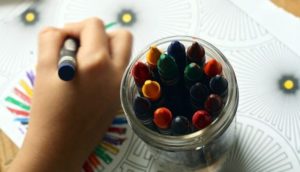 A child's hand and some crayons.