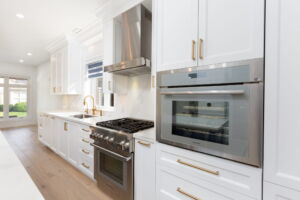 Beautifully appointed Etobicoke kitchen with white cabinetry, contrasting island, quartz backsplash and elegant gold-toned hardware at 28 Martin Grove Road