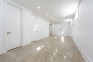 Finished basement recreation area with radiant in-floor heating and modern recessed lighting in this custom-rebuilt residence at 28 Martin Grove Road