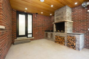 Distinctive secondary indoor kitchen at 28 Martin Grove Road featuring exposed brick walls and a substantial wood-burning cooking fireplace