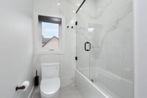 Contemporary family bathroom with glass-enclosed bathtub and shower, illuminated mirror and modern black fixtures at 28 Martin Grove Road Etobicoke real estate listing